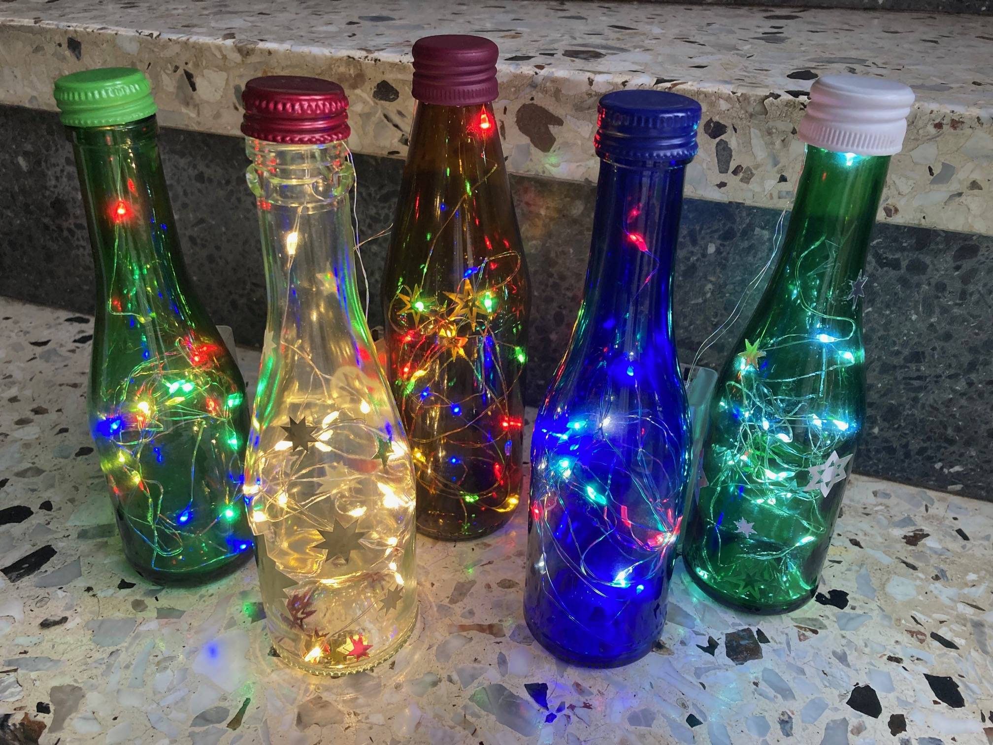 Bunte upgecycelte Flaschen mit Lichtern